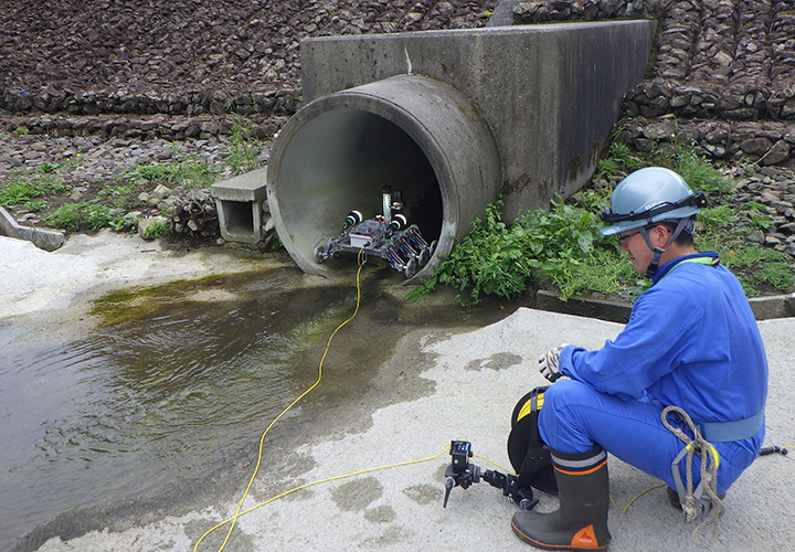 コントローラーを操縦し、排水管管口より探査車が進入するところです。